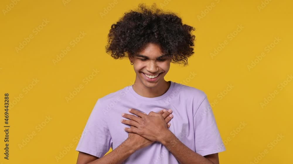 Smiling good kind surprised happy young curly african american man 20s years old wears white t-shirt ask who me oh it so sweet put hands on chest isolated on plain yellow background studio portrait Smiling good kind surprised happy young curly african american man 20s years old wears white t-shirt ask who me oh it so sweet put hands on chest isolated on plain yellow background studio portrait