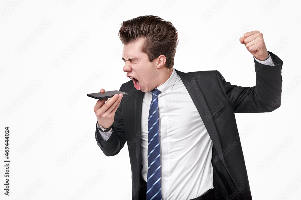 Expressive businessman recording voice message and celebrating success Expressive businessman recording voice message and celebrating success