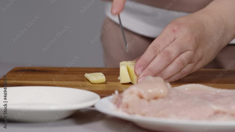 cook on the kitchen board slices mozzarella cheese and puts a on a white saucer close-up cook on the kitchen board slices mozzarella cheese and puts a on a white saucer close-up
