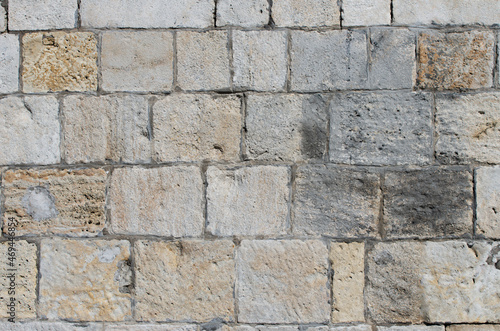 An old wall made of shell rock bricks connected by cement.