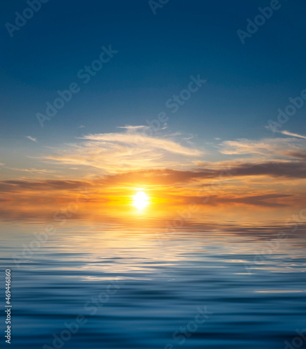 Amazing dawn in a clear sky with a bright sun in the clouds above the sea waves.