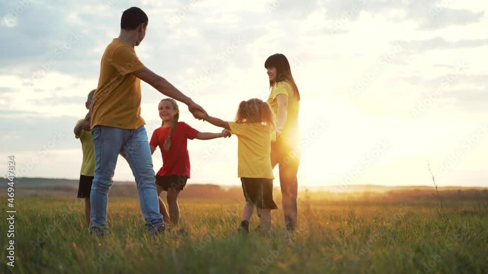 Happy family concept. Group of people hold hands in round dance. Children and parents are play in park on grass. Active lifestyle concept Family on green grass. Happy children play round dance in park Happy family concept. Group of people hold hands in round dance. Children and parents are play in park on grass. Active lifestyle concept Family on green grass. Happy children play round dance in park