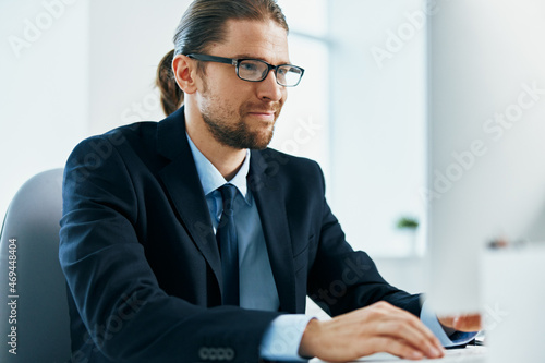 business man with glasses in a suit works at the computer in the office