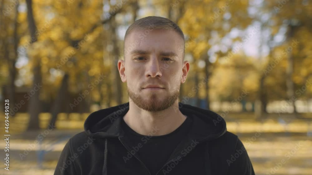 Close up portrait of young peaceful bearded man looking at camera, posing in bright golden autumn park Close up portrait of young peaceful bearded man looking at camera, posing in bright golden autumn park