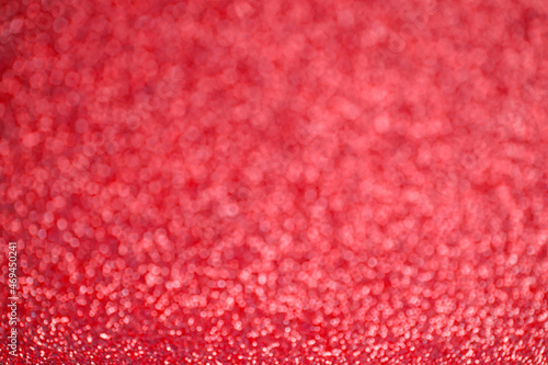 Glitter red background. Texture foil and confetti bokeh, light of red dust. Festive party Christmas and new year's eve background.