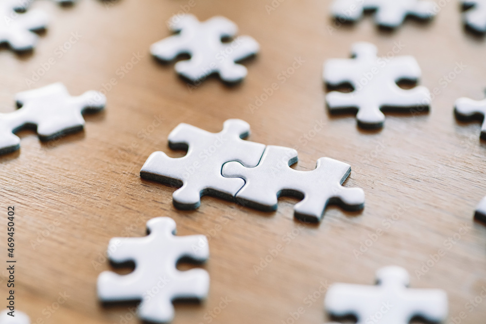 Obraz premium Puzzle pieces are connected. White puzzle pieces on a wooden table background. Business, partner, solution, alliance, union concept.