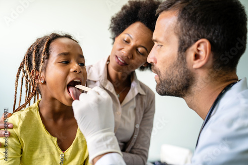 Pediatrician examining a little african girl at hospital. Healthcare, people concept