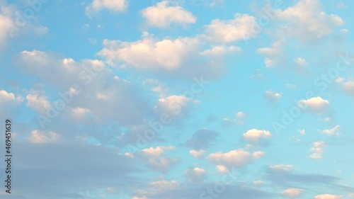 Small fluffy white clouds in a golden - blue sky during sunset