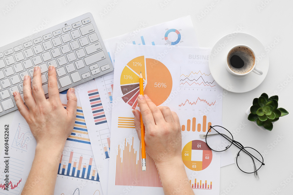 Woman with computer keyboard, business charts and cup of coffee on white background