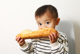 大きなフランスパンを食べているカワイイ男の子。