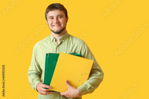 Young man with folders on color background