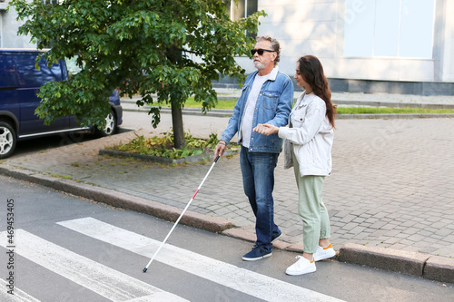 Blind senior man with his daughter crossing road in city photo