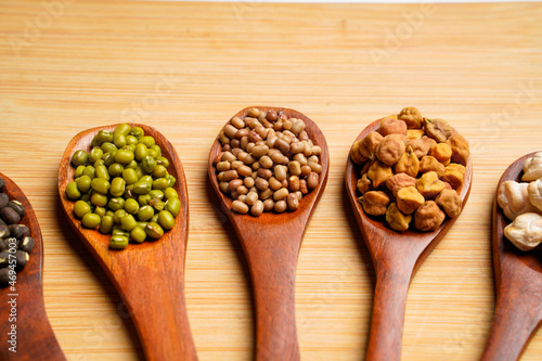 various dried types of bean and pea in wooden spoon.