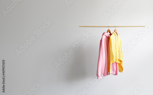 Modern hoodies hanging on light wall