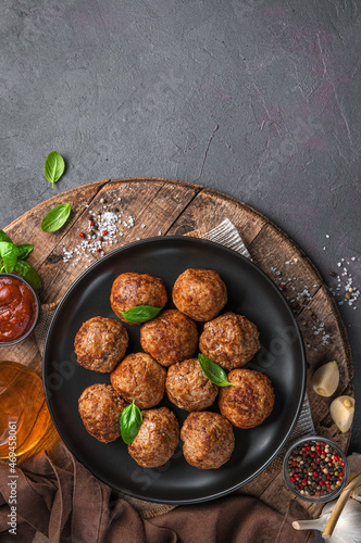 A plate of fried meatballs with basil on a wooden board.