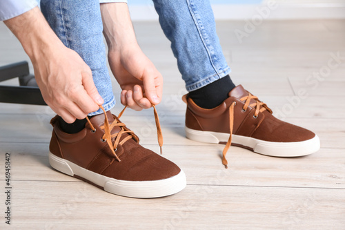 Man tying shoe laces at home, closeup