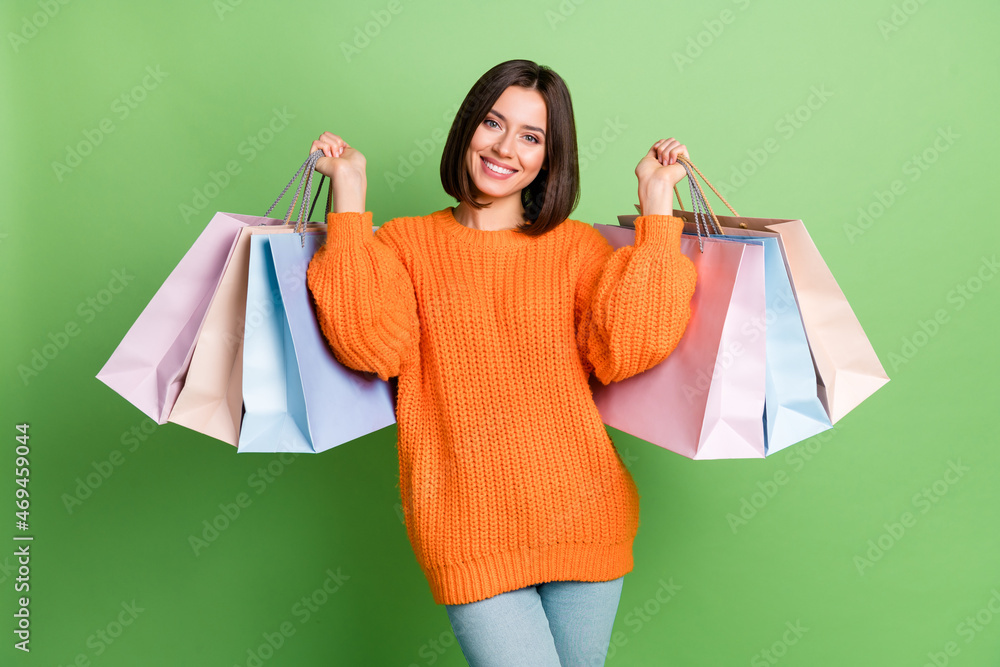 Portrait of attractive cheerful girl holding new things consumerism market isolated over bright green color background