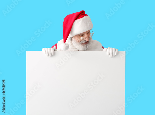 Santa Claus with blank poster on color background © Pixel-Shot