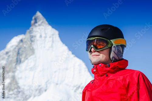 Happy man snowboarder posing with mountain landscape