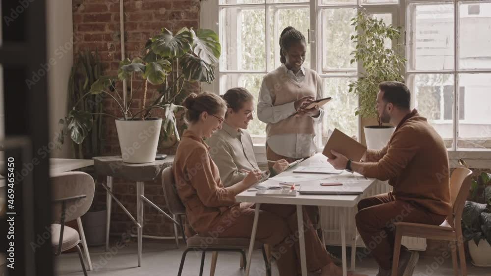Slowmo shot of multiethnic group of young creative designers discussing project working together in modern design agency Slowmo shot of multiethnic group of young creative designers discussing project working together in modern design agency