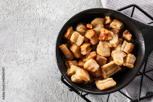 Frying pan with tasty cracklings on light background