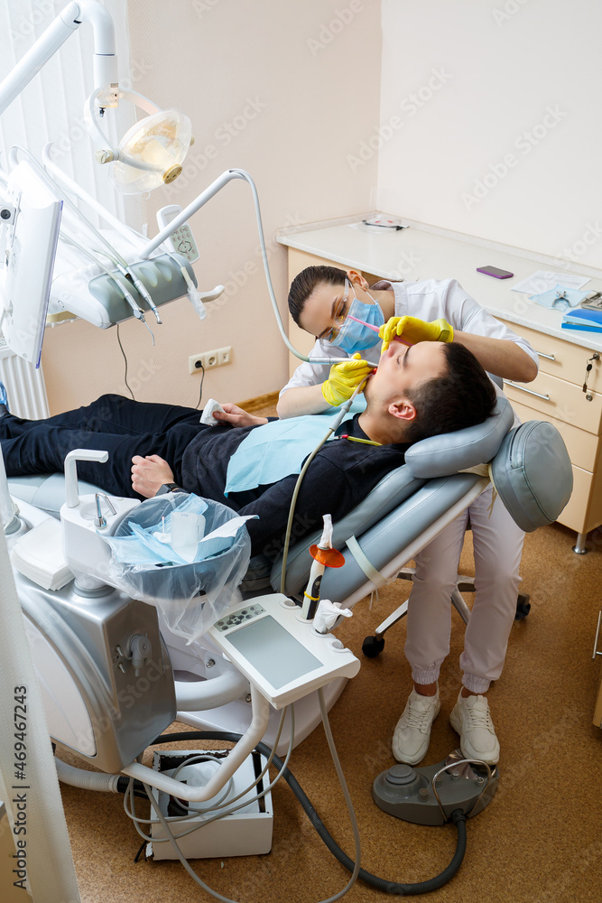 The dentist in the office treats the teeth of the patient who is in the dental chair. dentistry. The dentist puts a dental filling on his patient. Oral care The dentist in the office treats the teeth of the patient who is in the dental chair. dentistry. The dentist puts a dental filling on his patient. Oral care
