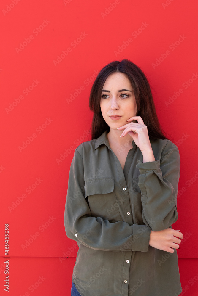 Young Brunette woman wearing a casual green shirt in a red Background Young Brunette woman wearing a casual green shirt in a red Background