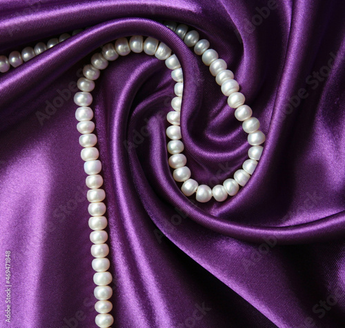 White pearls on a lilac silk as background