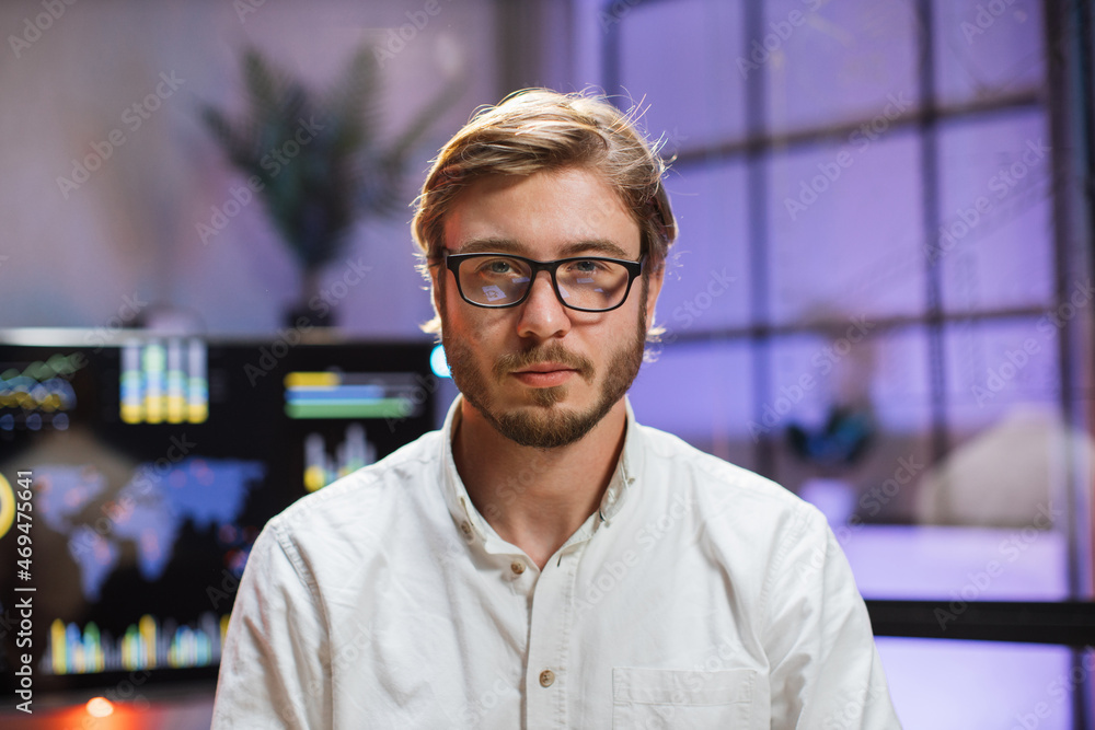 Portrait of confident caucasian man in eyeglasses and white shirt sitting at office desk. Company worker with beard looking at camera. Concept of people and business. Portrait of confident caucasian man in eyeglasses and white shirt sitting at office desk. Company worker with beard looking at camera. Concept of people and business.