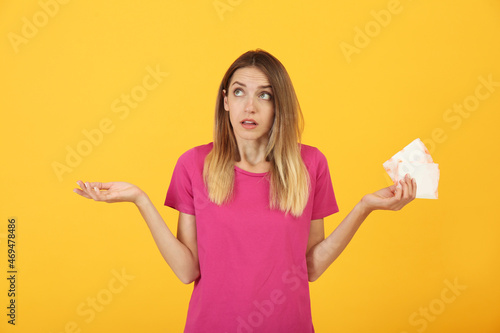 Thoughtful young woman with disposable menstrual pads on yellow background