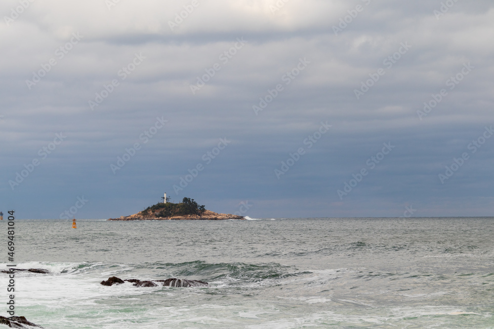 A small island floating on the cloudy sky and sea.
