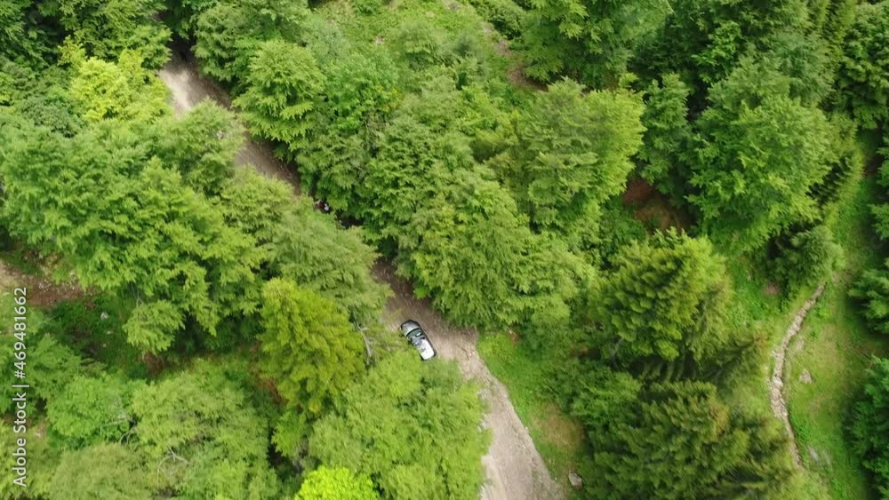 4K Aerial view of a grey color SUV all terrain car driving on a dirt road through the mountains between tall trees in an amazing summer landscape. 4K Aerial view of a grey color SUV all terrain car driving on a dirt road through the mountains between tall trees in an amazing summer landscape.