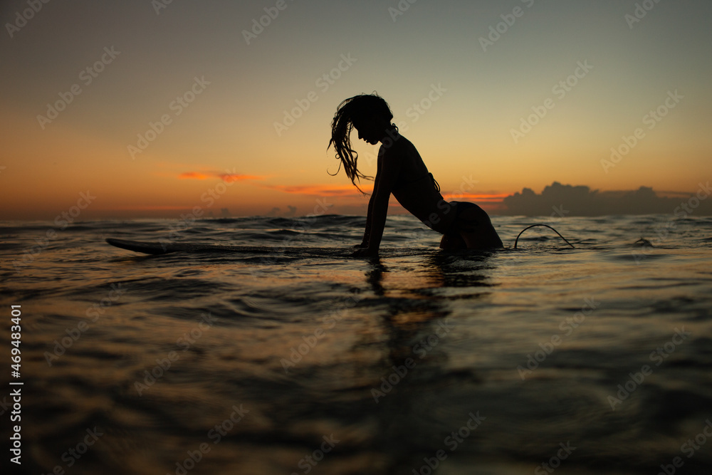 beautiful girl with a surfboard at sunset.