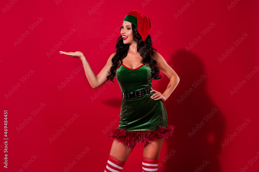 Photo of provocative babe palm demonstrate empty space option wear hat elf costume isolated red color background Photo of provocative babe palm demonstrate empty space option wear hat elf costume isolated red color background
