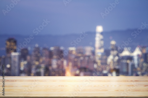 Empty wooden tabletop with beautiful blurry skyscrapers at evening on background  mock up