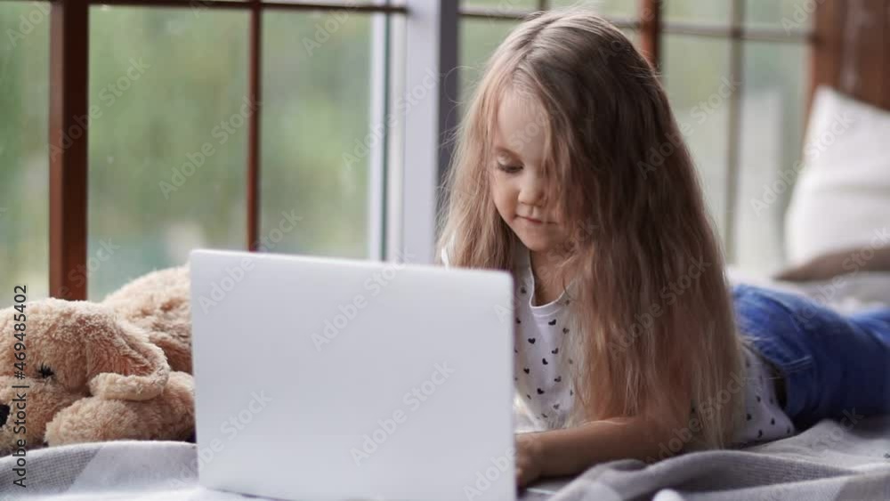 Cute little girl sitting at a laptop at home. Children. Cute little girl sitting at a laptop at home. Children.