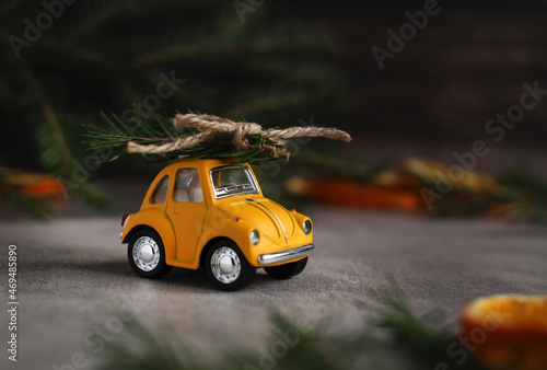 Fototapeta Naklejka Na Ścianę i Meble -  yellow retro car with spruce branches on a gray background