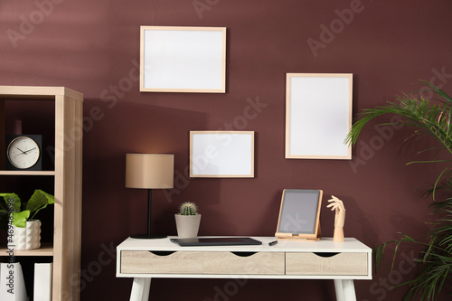 Empty frames hanging on brown wall indoors. Mockup for design © New Africa