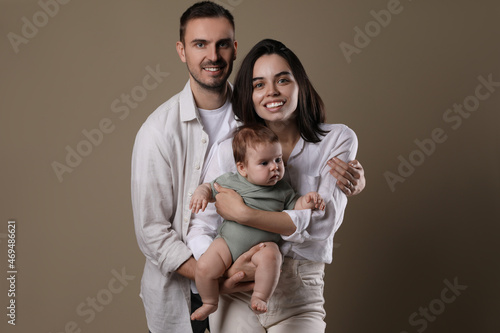 Happy family. Couple with their cute baby on beige background