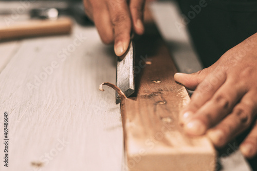 Hands working on a wood strip with a chisel photo