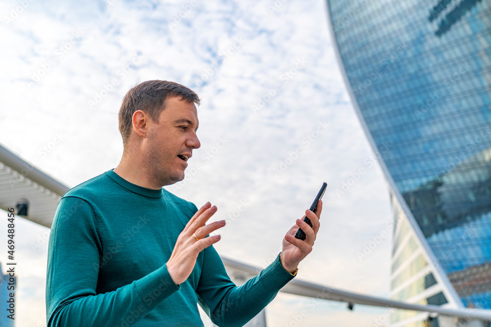 Fototapeta premium Handsome millennial man cell phone call outdoor city street. Close up portrait of happy mature guy talking on cell phone and smiling