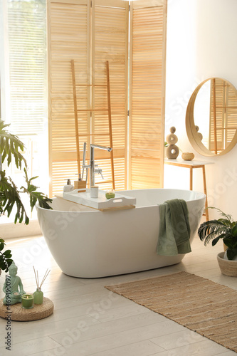 Stylish bathroom interior with modern tub  window and beautiful houseplants. Home design