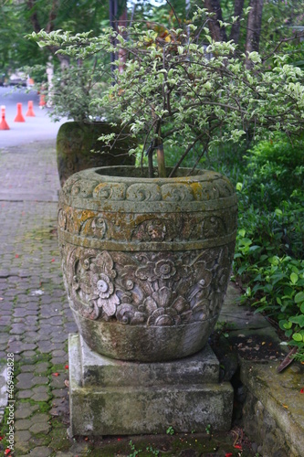 A large flower pot which on the outside contains a Balinese carving motif that adds to the vintage impression where this pot is placed in a Denpasar city park