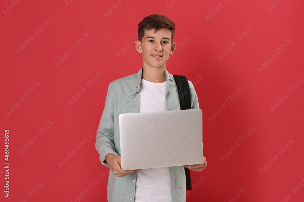 Teenage student with backpack and laptop on red background Teenage student with backpack and laptop on red background