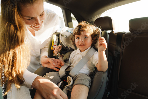 White woman smiling while wearing seat-belt her son