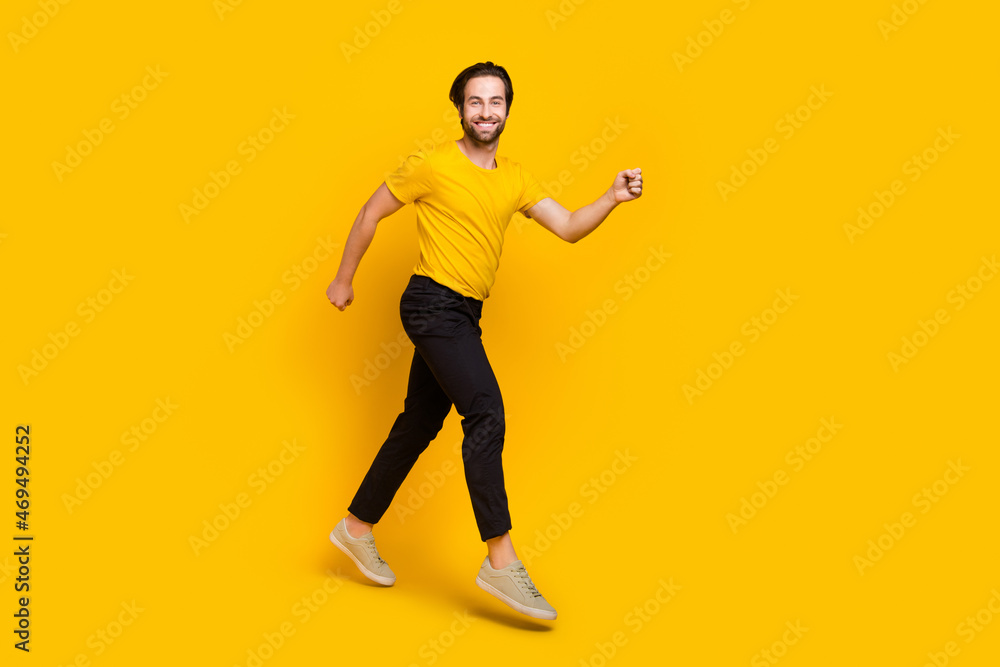 Full length profile side photo of young cheerful guy have fun action movement runner isolated over yellow color background