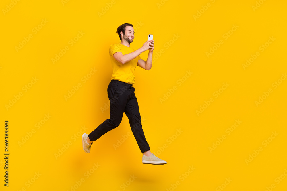 Full size profile side photo of young addicted guy chat type cellphone 4g post like walk jump isolated over yellow color background
