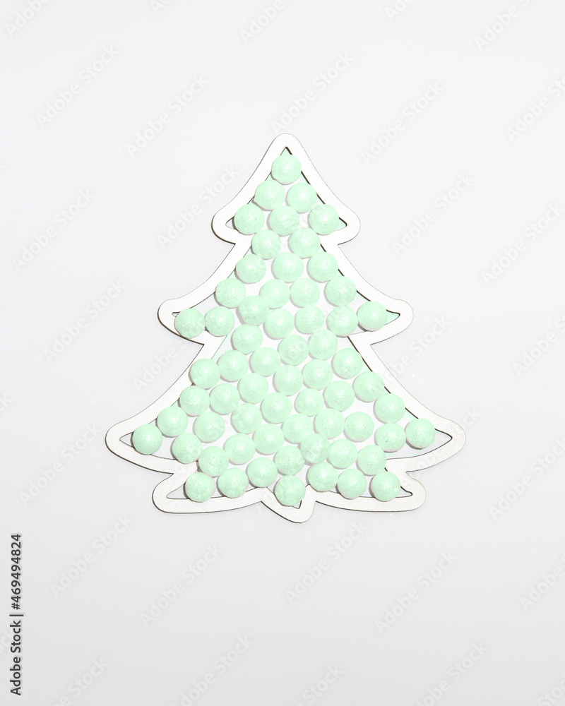 Christmas tree shape frame filled with snow sparkle green neon colour balls ornaments against white background. Minimal winter holidays and New Year concept. Christmas tree shape frame filled with snow sparkle green neon colour balls ornaments against white background. Minimal winter holidays and New Year concept.