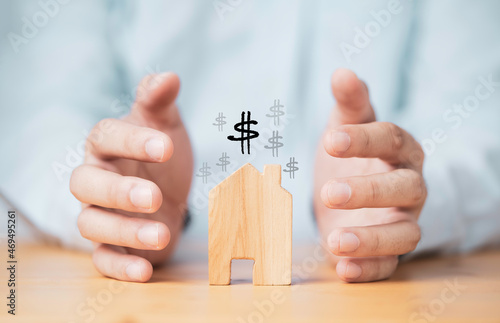 Businessman hand protecting house model for insurance of asset concept.