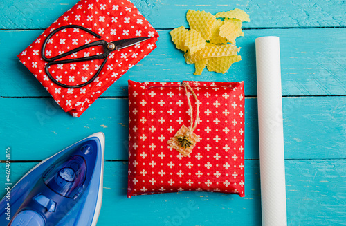 Take away sandwich inside homemade beeswax wraps. Wrapping food in handmade beeswax wrap cloth indoors, alternative for plastic. Using iron machine to melt beeswax into cotton cloth. photo